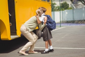 Mother hugging her daughter by school bus